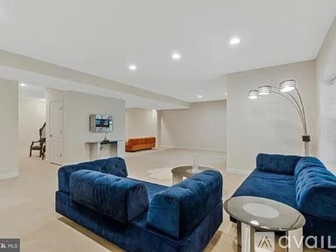 A living room with blue velvet chairs and a television.