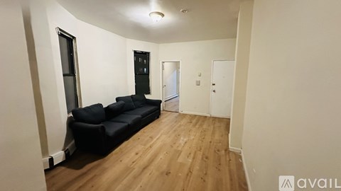 A living room with a black couch and wooden floors.