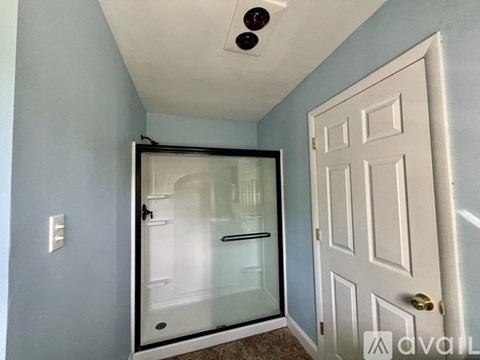 A white door is on the right side of a glass shower enclosure.