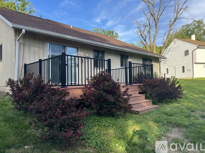 A house with a black railing and steps leading to the front door.