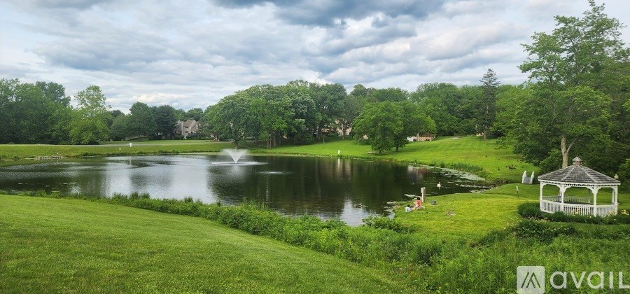 A serene park with a pond, a gazebo, and a fountain.