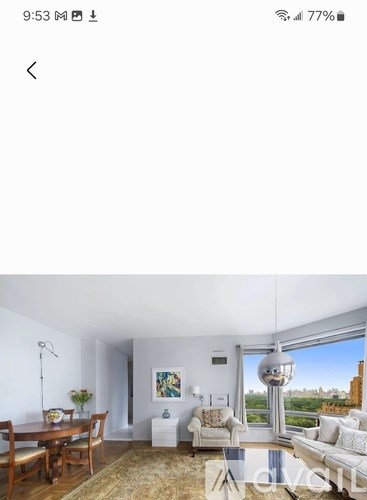 A living room with a dining table and chairs, a couch, a side table, and a large window with a view of the city.