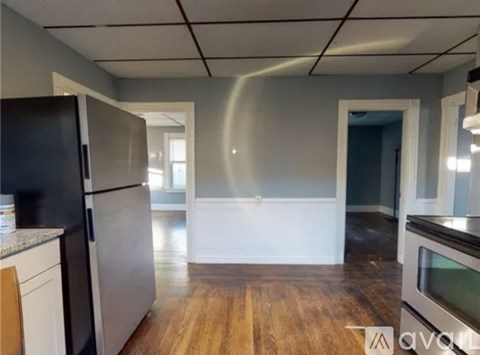 A kitchen with a black refrigerator and wooden floors.