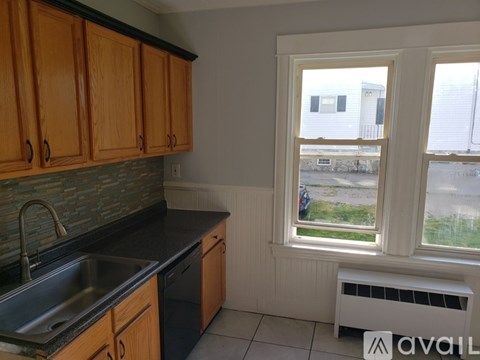 A kitchen with wooden cabinets and a window overlooking a parking lot.