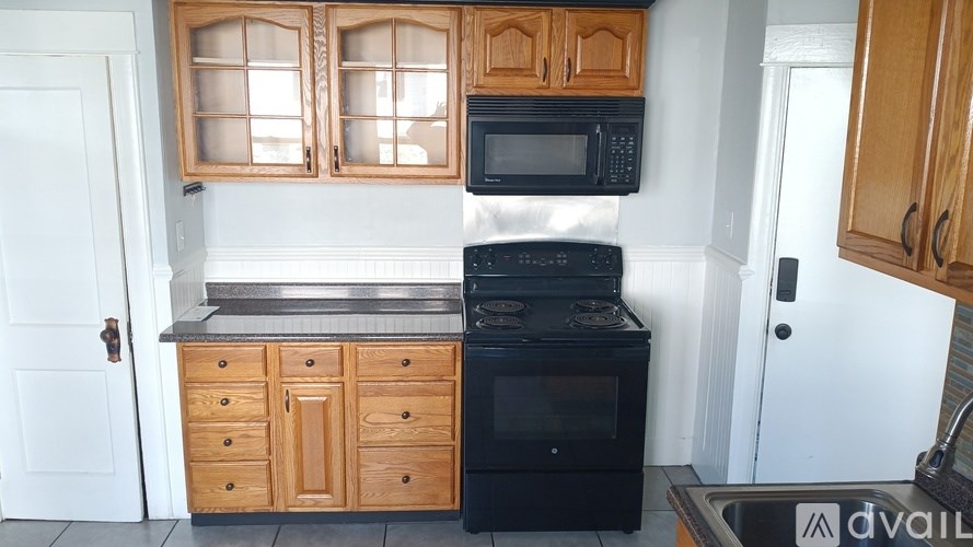 A kitchen with wooden cabinets and black appliances.