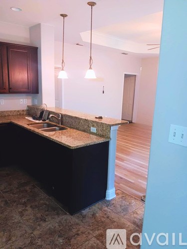 A kitchen with a granite countertop and dark brown cabinets.