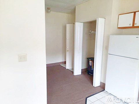 A white refrigerator is in a kitchen with brown flooring.