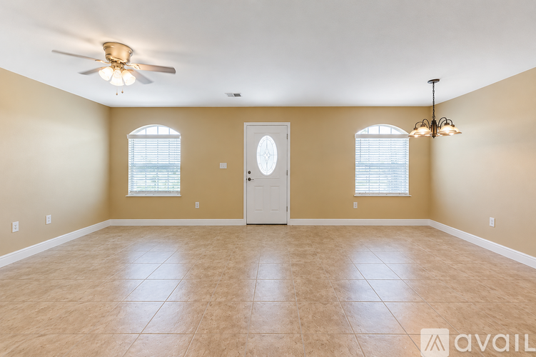 A room with a door, two windows, and a ceiling fan.