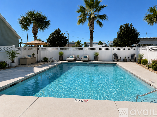 A pool surrounded by a white fence and palm trees.