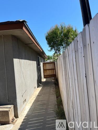 A wooden fence runs along the side of a concrete building.