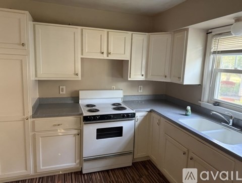 A kitchen with white cabinets and a stove top oven.
