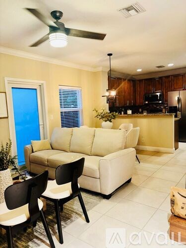 A living room with a white couch and two black chairs.
