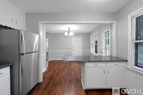 A kitchen with white cabinets and a wooden floor.