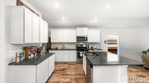 A kitchen with white cabinets and a granite countertop.