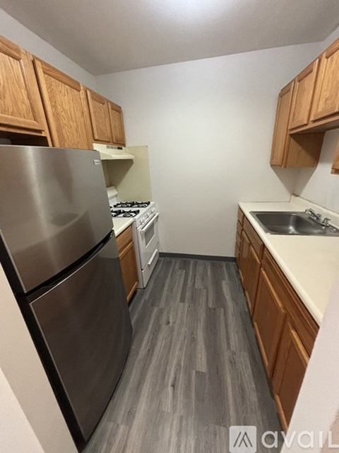 A kitchen with wooden cabinets and a stainless steel refrigerator.