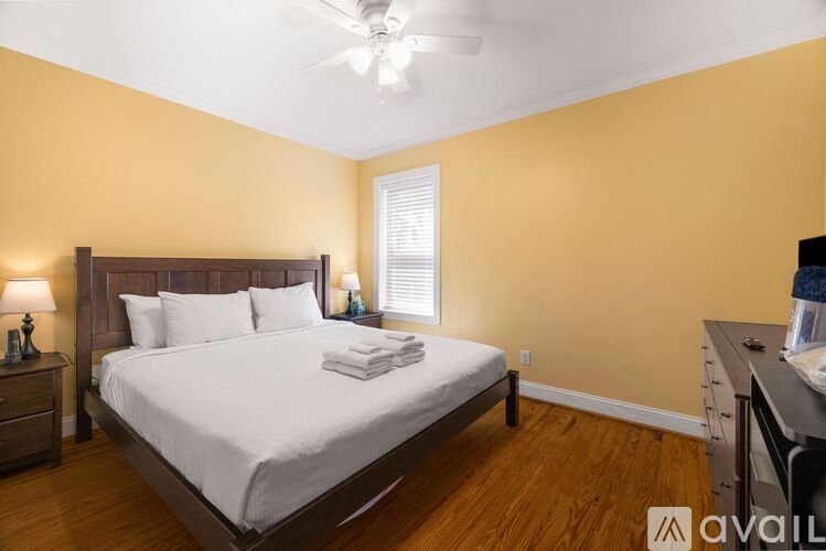 A bedroom with a bed, nightstand, and a window with blinds.