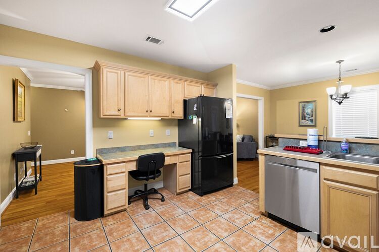 A kitchen with a black refrigerator and brown cabinets.