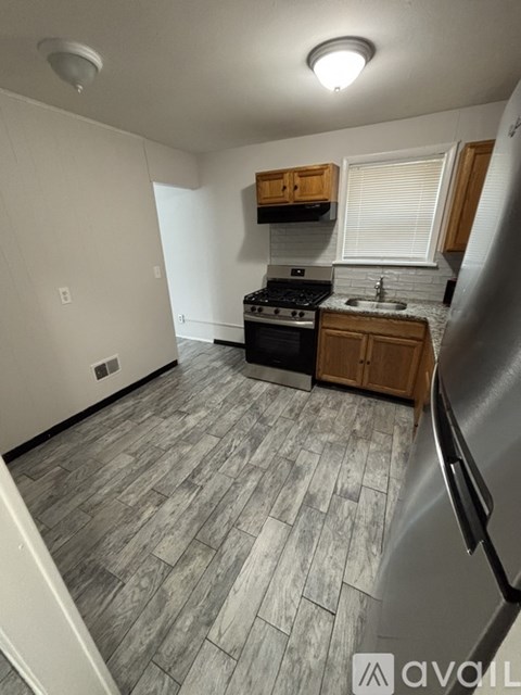 A kitchen with a stove, sink, and refrigerator.