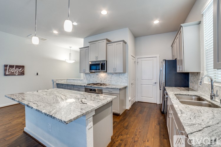 A kitchen with a granite countertop and a wooden floor.