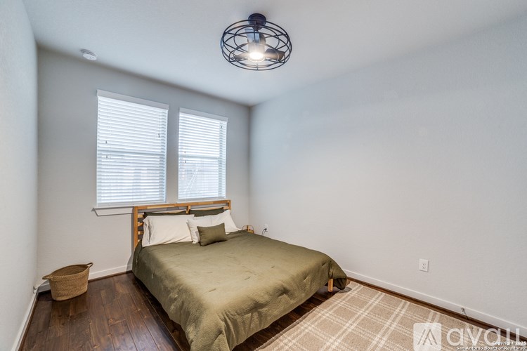 A bedroom with a bed, pillows, a basket, and a ceiling light.