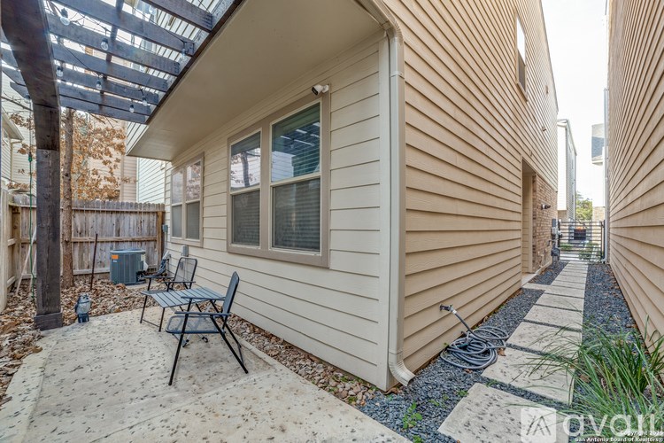 A patio with a chair and a table is in front of a house.