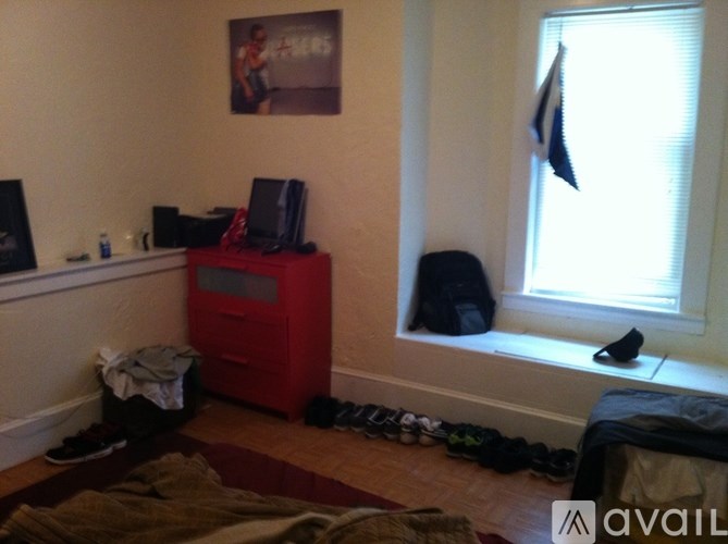 A room with a red cabinet, a window with a flag hanging from it, and a picture on the wall.