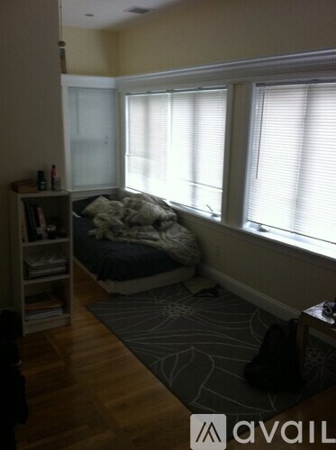 A bedroom with a bed, a bookshelf, and a window.