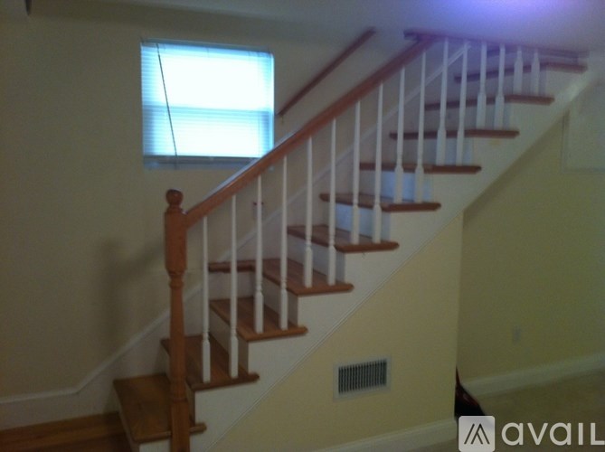 A wooden staircase with white railings leads up to a window.
