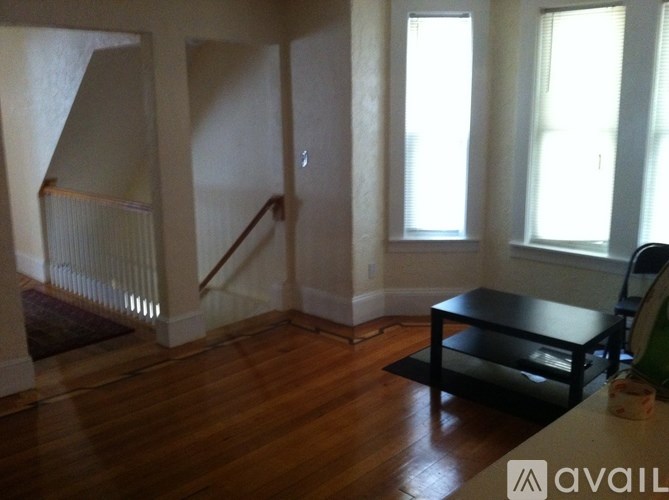 A room with wooden floors and a staircase leading to another floor.