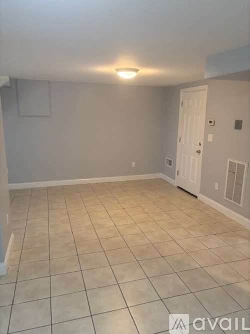 A bedroom with a bed, a window with blinds, a door, a laundry basket, a pair of shoes, a bookshelf, and a map on the wall.