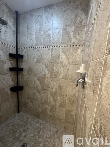 A bathroom with a tiled shower and a black pipe.