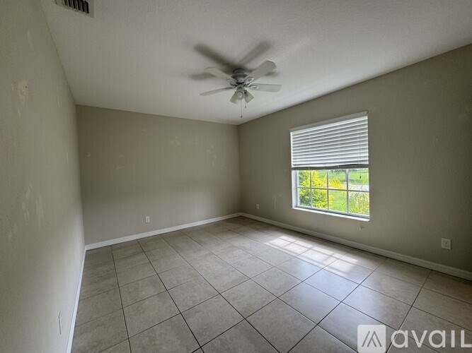 A room with a ceiling fan and a window with blinds.