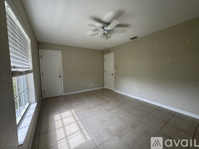 A room with a ceiling fan and tile flooring.