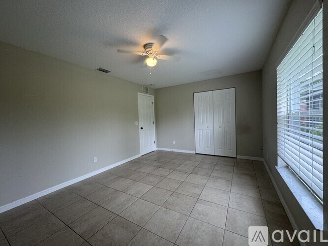A room with a ceiling fan and tile flooring.