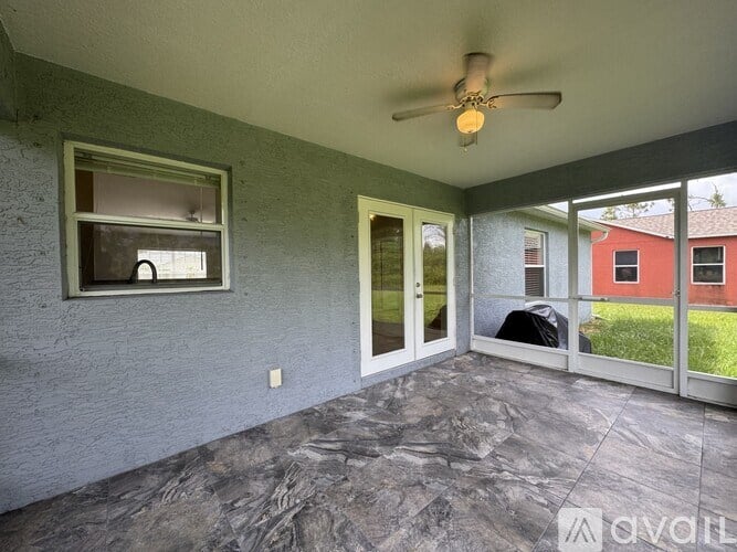 A patio with a ceiling fan and sliding glass doors.