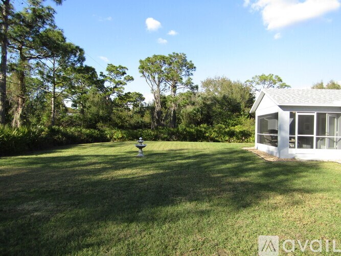 A house with a white fence and a green lawn in front of it.
