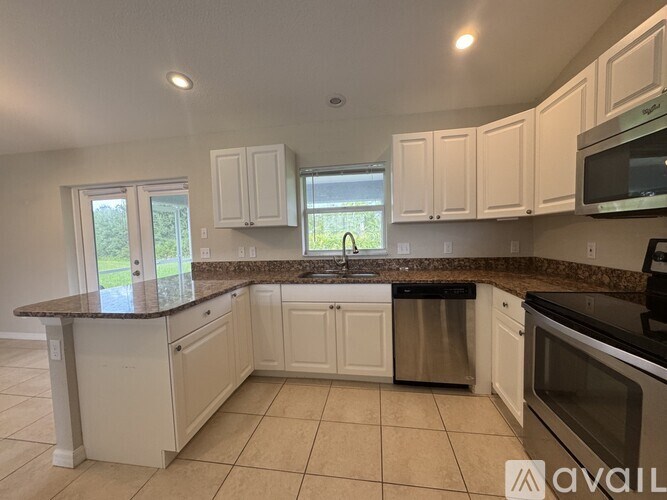 A kitchen with white cabinets and a granite countertop.