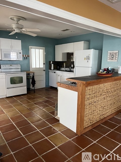 A kitchen with a tile floor and a ceiling fan.