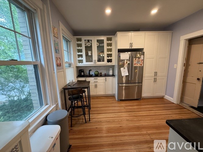 A kitchen with wooden floors and a stainless steel refrigerator.