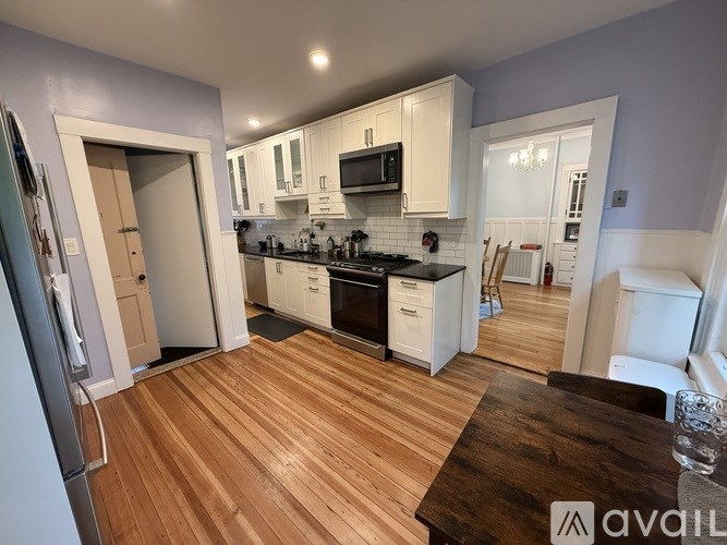 A kitchen with wooden floors and white cabinets.