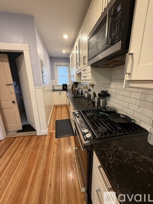 A kitchen with a black counter top and wooden floors.