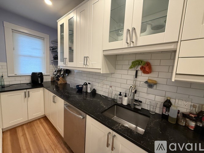 A kitchen with white cabinets and a black countertop.