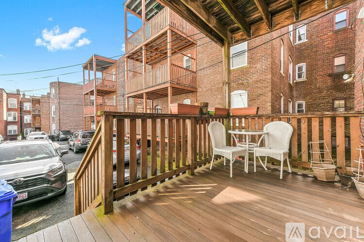 A wooden deck with chairs and a table is in front of a brick building.