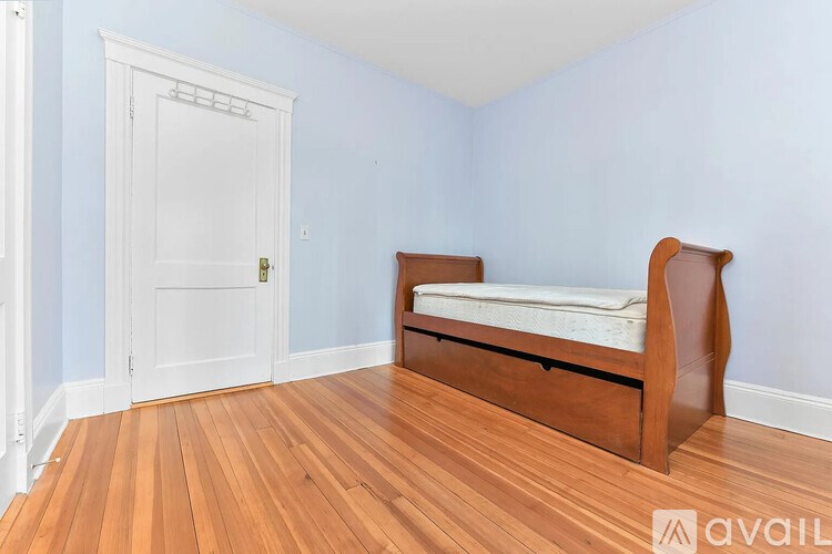 A bedroom with a bed, wooden floors, and a white door.