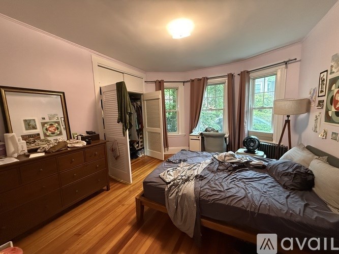 A bedroom with a bed, dresser, and window with curtains.