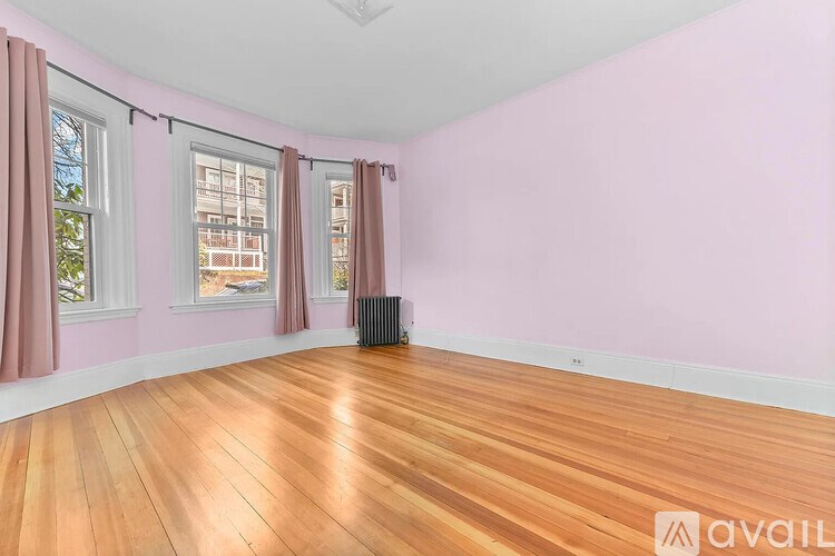 A room with pink walls and wooden flooring is available for rent.