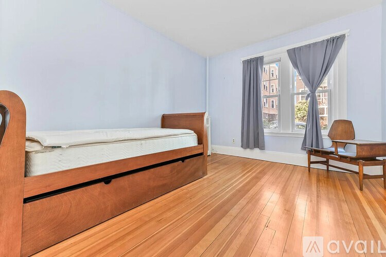 A bedroom with a bed, chair, and window.