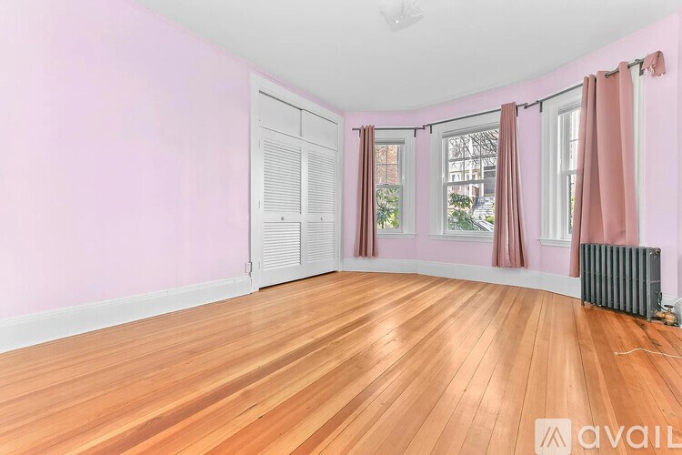 A room with pink walls and wooden flooring.