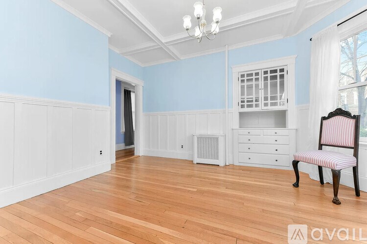 A room with a wooden floor and a white chair with a red and white striped cushion.