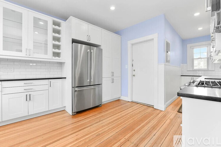 A kitchen with white cabinets and a stainless steel refrigerator.